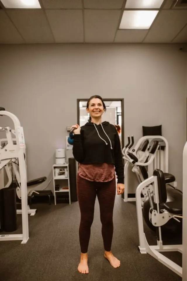 Une sportive s'entraîne avec une kettlebell en salle.