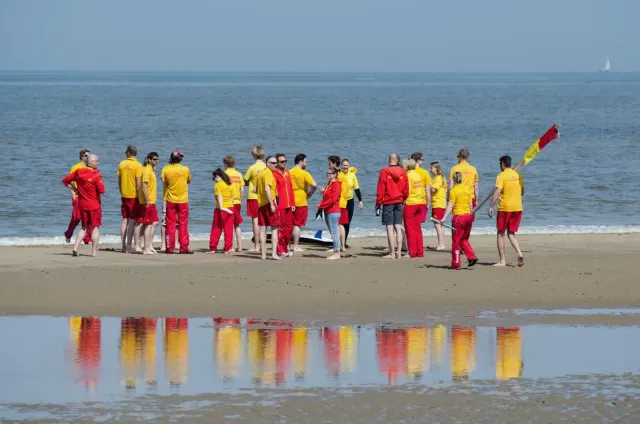 Un groupe de sauveteurs en tenues jaunes et rouges se rassemble sur une plage.