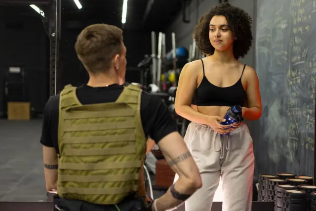 Un coach sportif échange avec une cliente dans une salle de fitness.