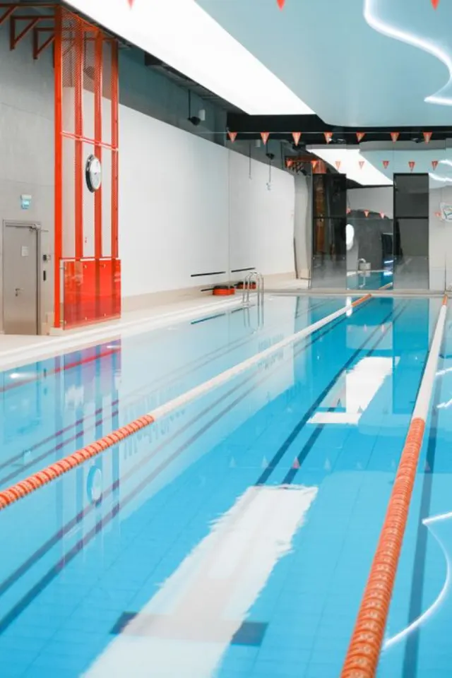 Une piscine intérieure lumineuse avec des lignes de nage et un plafond réfléchissant.